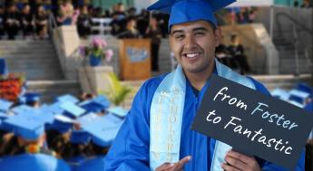 Graduate holding sign reading "From Foster to Fantastic"